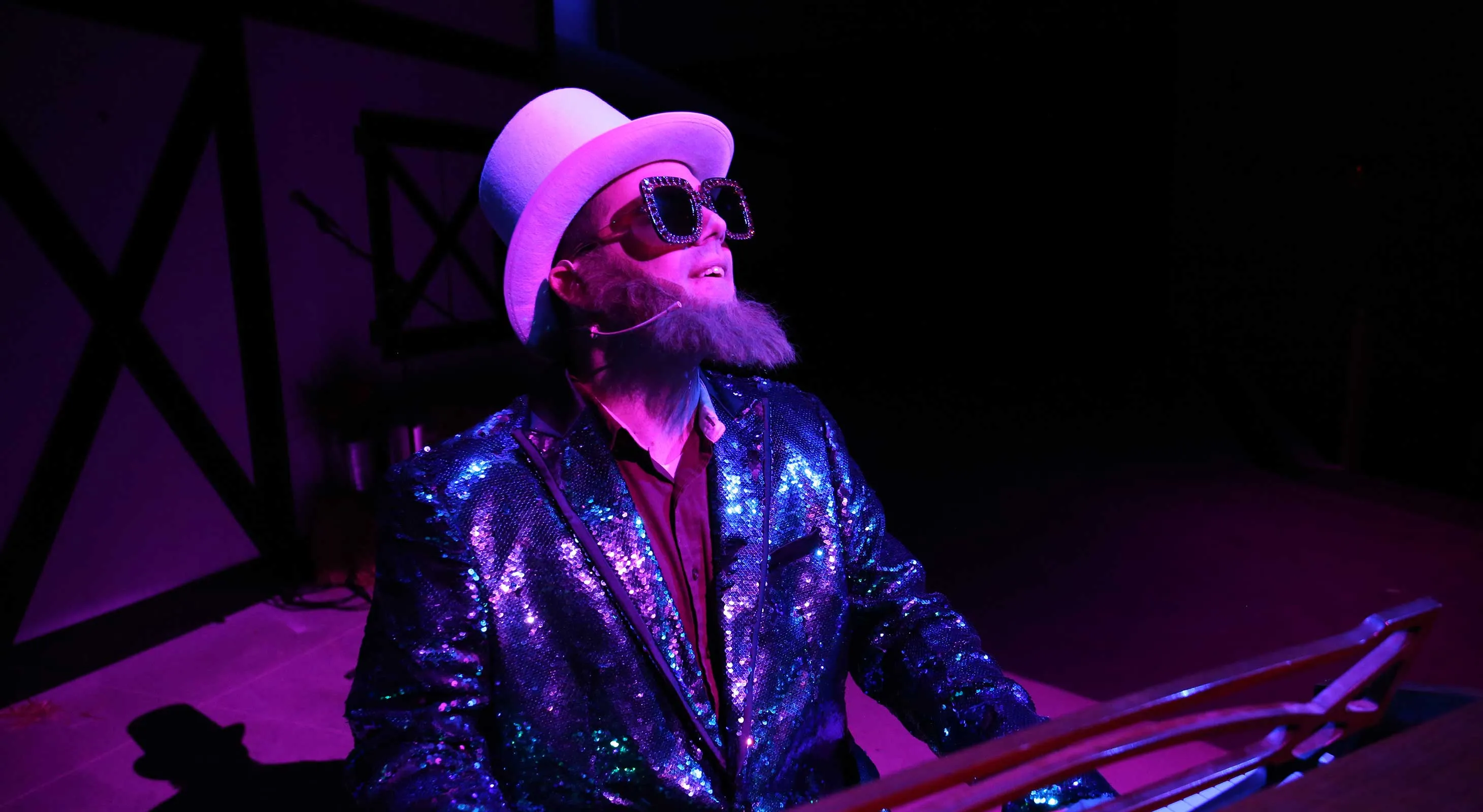 Amish performer in a top hat, sequin jacket and sunglasses